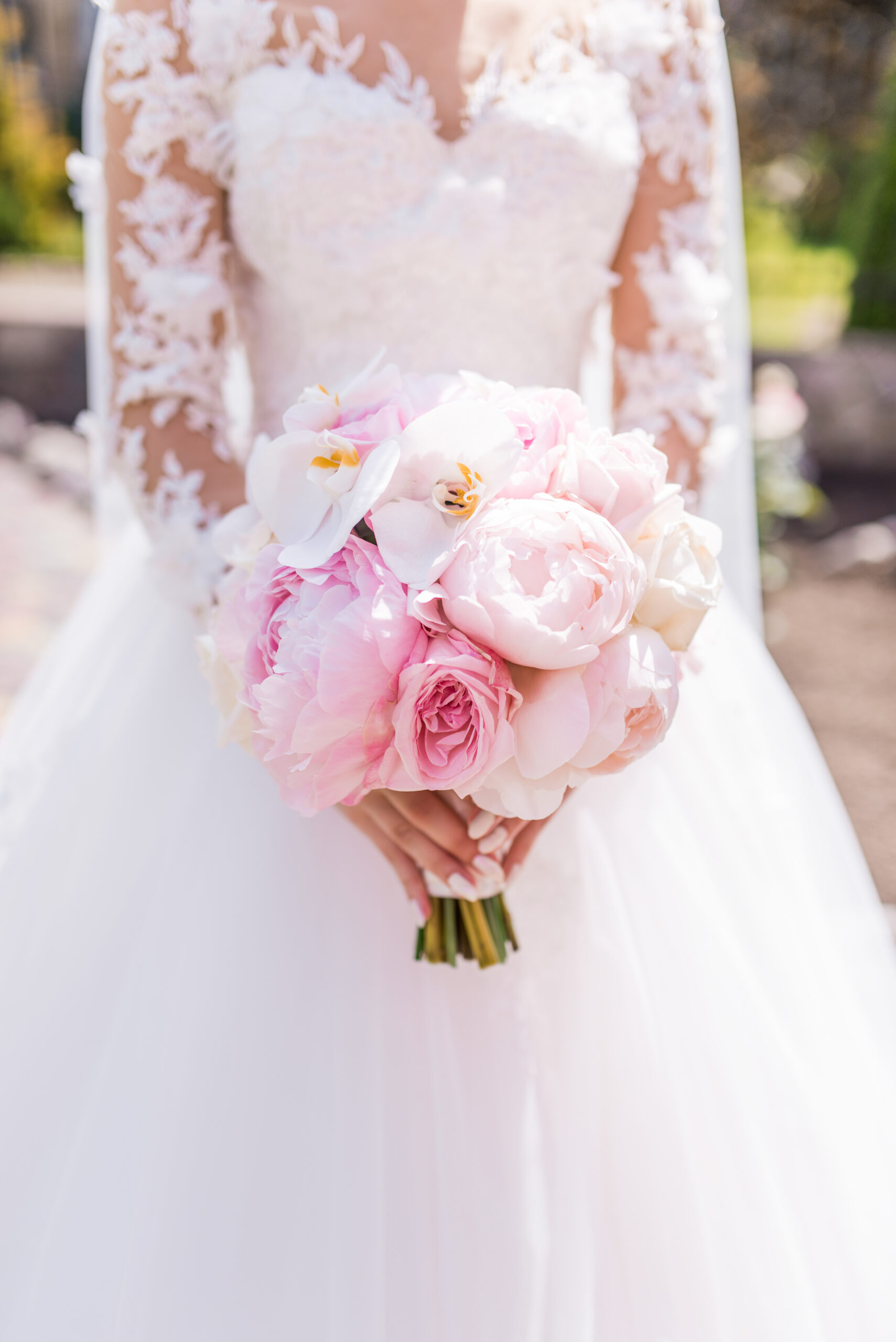 bride in rich dress holds pink wedding bouquet of orchids and pe